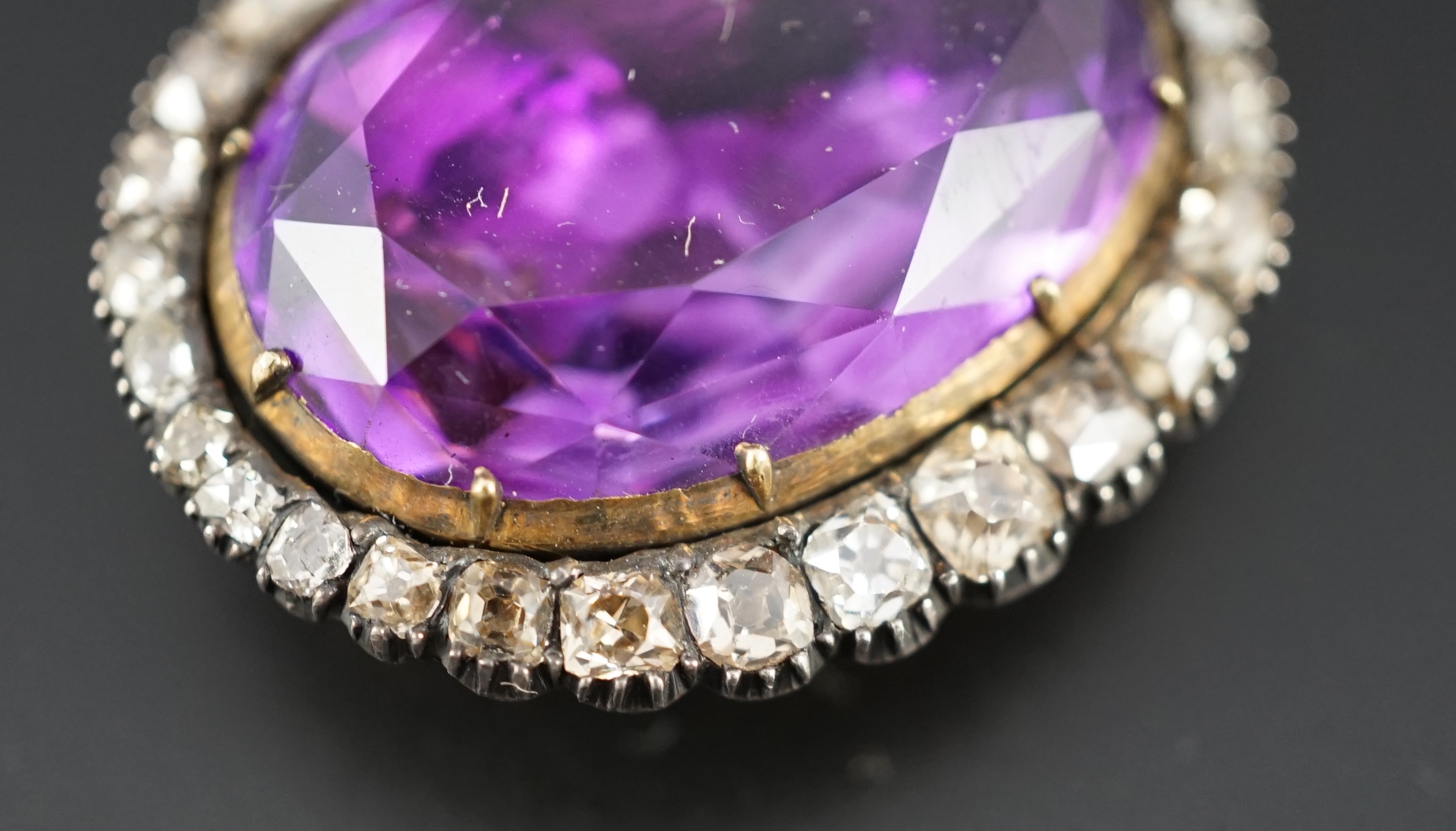 An early 19th century, gold and oval cut foil backed amethyst set pendant, with old cut diamond set border and closed back setting